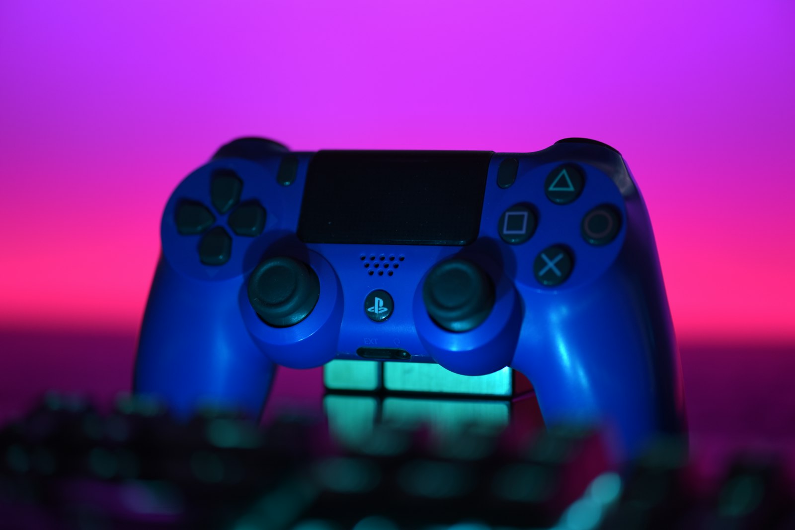 Blue game controller on a desk with a neon background